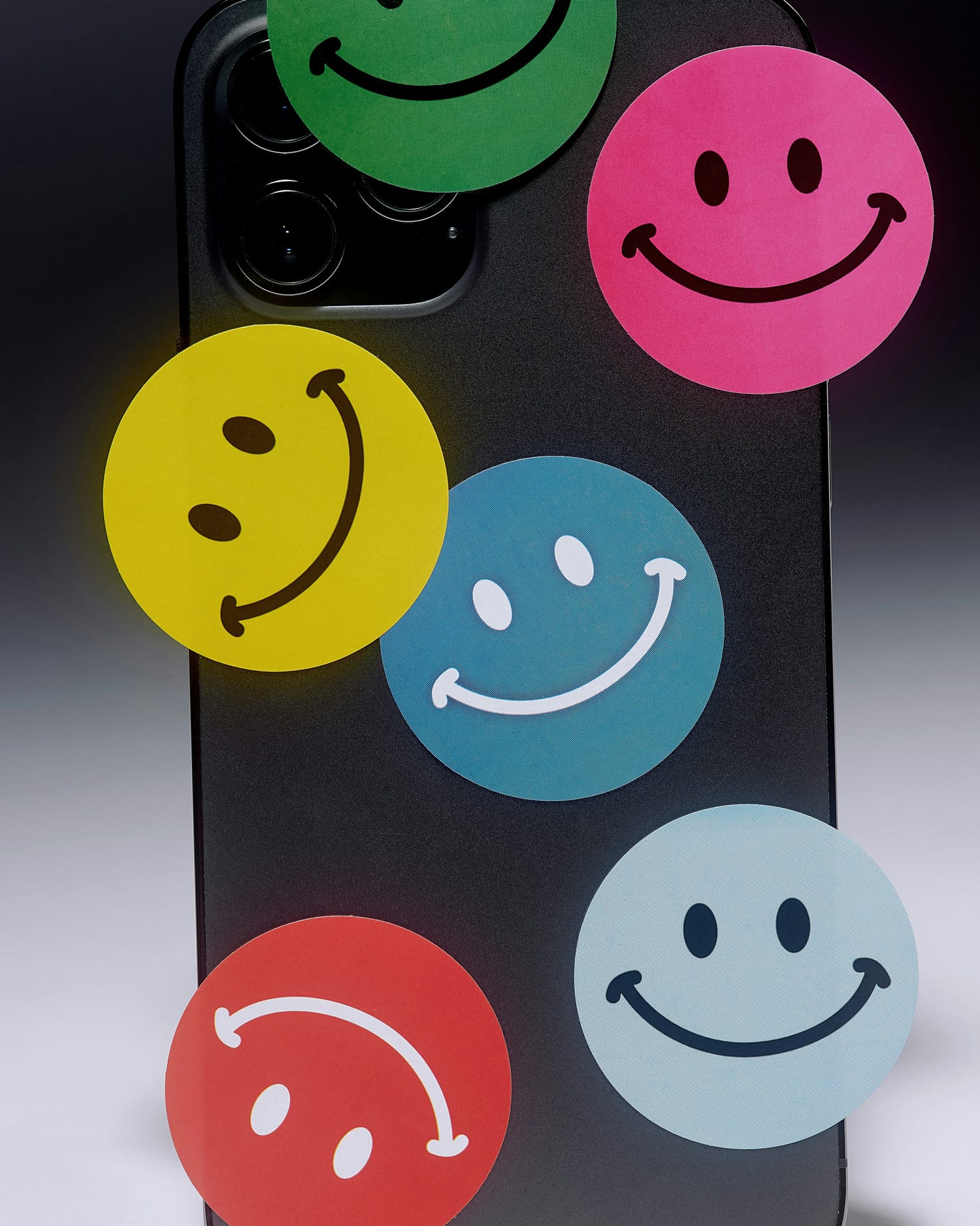 Close up of the back of an iPhone with several colorful smiley stickers on it. If you want to stop buying stuff, electronics is a good place to start. Consider if a new phone is necessary when being offered a new phone subscription.