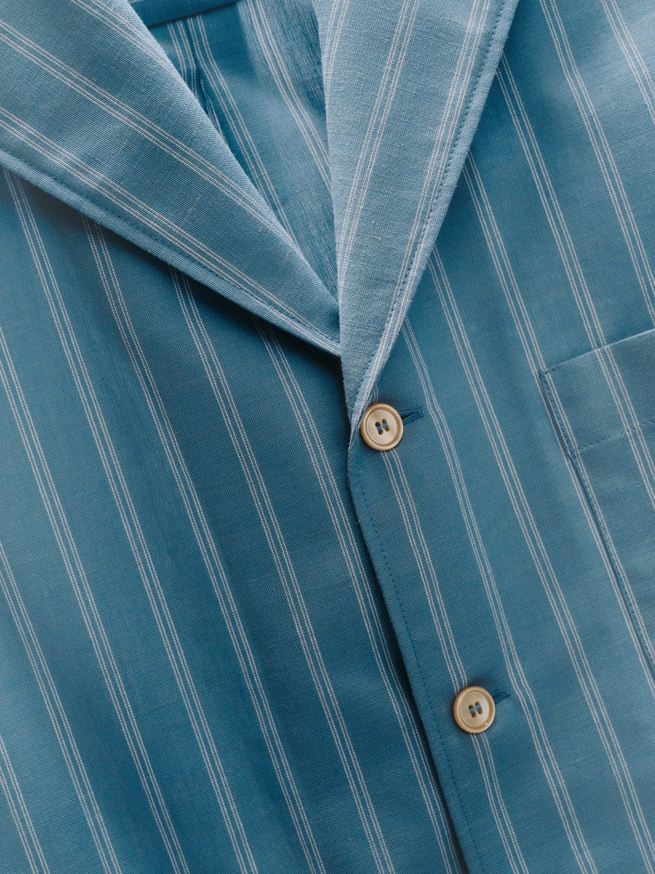 Close-up photo of a blue striped shirt. Some clothes aren't designed to last long, so buying less and better quality is a good idea.